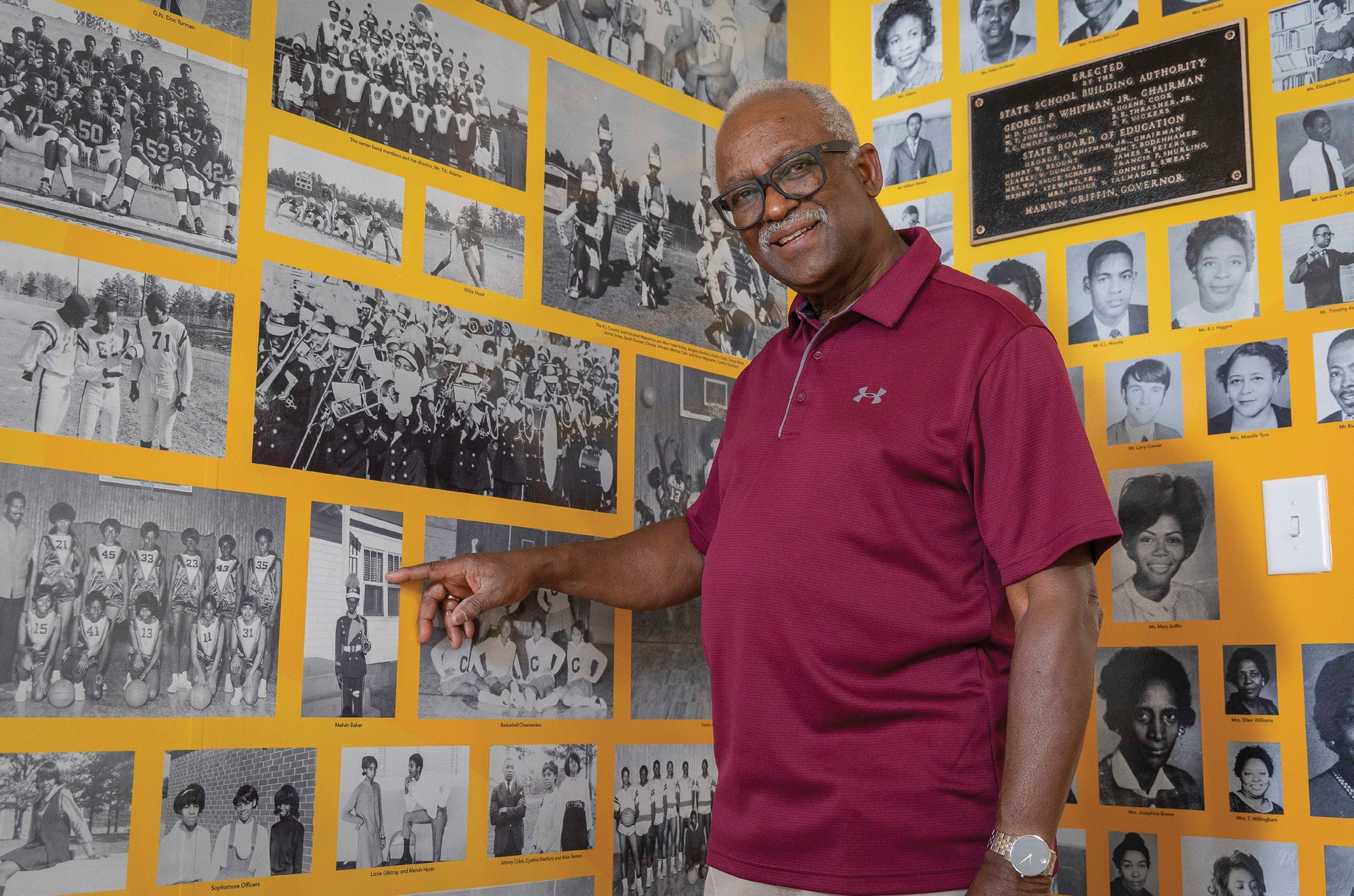 (no caption — Dr. Melvin Baker at the Baker School heritage wall)
